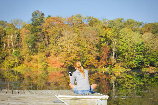 A woman too busy looking at her phone to notice the natural fall beauty all around her.