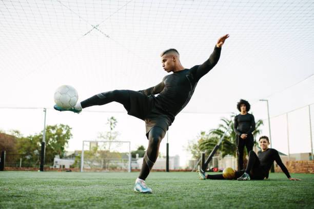 spieler treten fußball auf feld - soccer teenager team ball stock-fotos und bilder