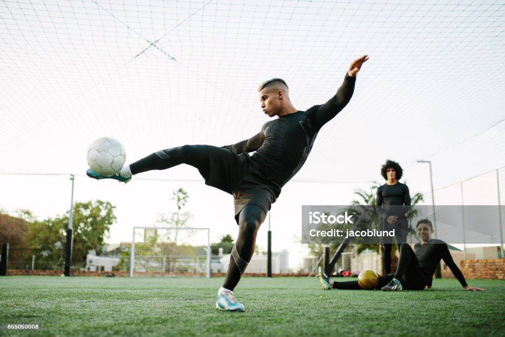 Player kicking soccer ball on field Soccer player kicking ball. Young footballer practicing on football field. Soccer Stock Photo