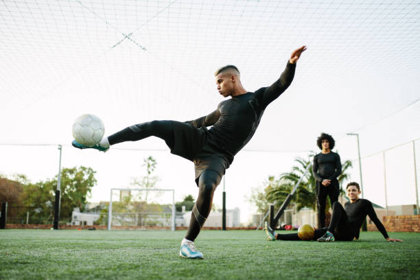 Player kicking soccer ball on field Soccer player kicking ball. Young footballer practicing on football field. soccer soccer ball kicking adult stock pictures, royalty-free photos & images