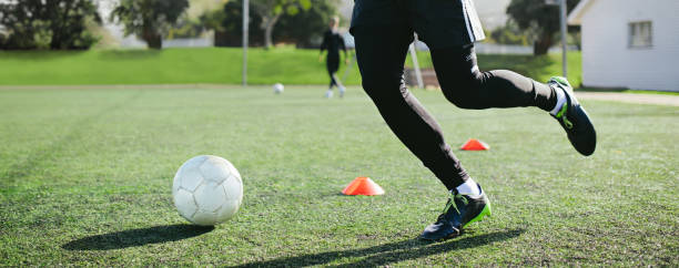 Leg skill training on football field Leg skill training on football field. Low angle view of young soccer player running in football field leading ball between row of cones during practice. softball pitcher stock pictures, royalty-free photos & images