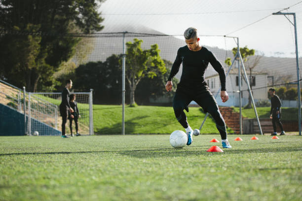 pratique de joueur de football dribbles sur champ - sentraîner photos et images de collection