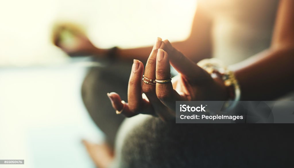 You can do anything you put your mind to Shot of a young woman practicing yoga in the studio Meditating Stock Photo