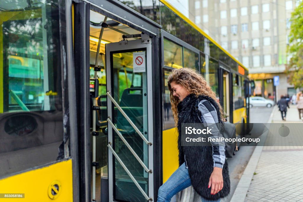 Young woman stepping into the bus Young woman enters bus Bus Stock Photo