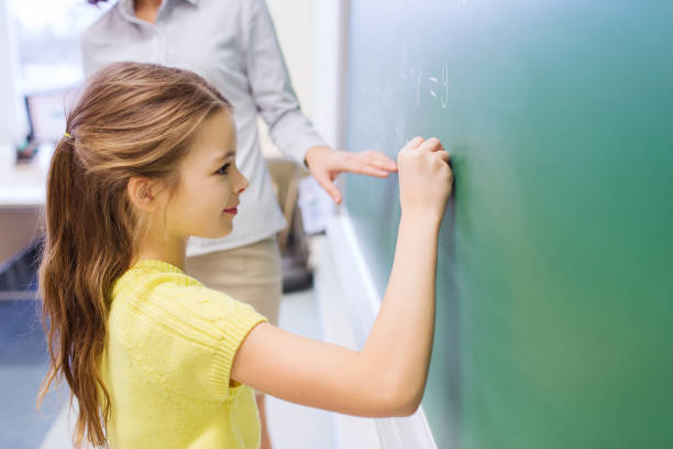 istock little smiling schoolgirl writing on chalk board 855061204