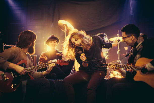 Group of people, men and woman,young band, playing music instrumenst, indoors on stage.Change guitar head