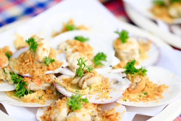 baked scallops with cheese topping fried garlic and boiled vegetable on plate