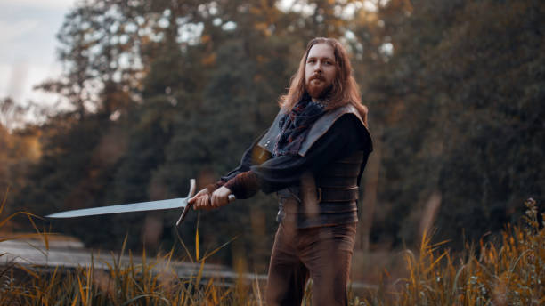 istock Knight in the forest. A guy in medieval costume with a sword 855063336