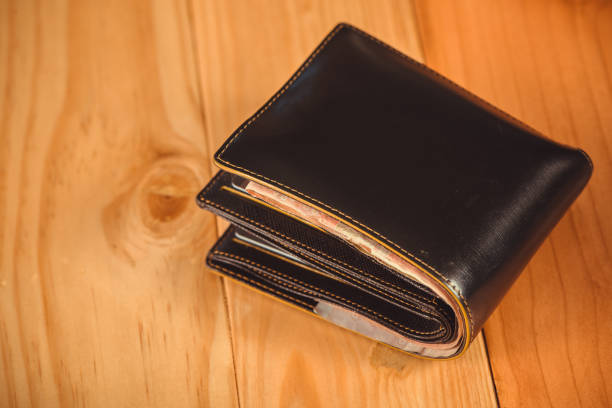 istock Black men leather wallet with banknotes on wooden table in vintage tone. 855065728