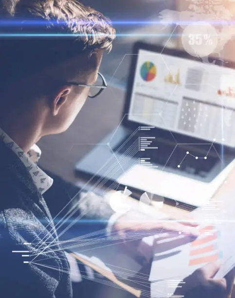 Photo of Young businessman analyze stock report on notebook screen.Concept of digital screen,virtual connection icon,diagram,graph interfaces on background.Vertical.