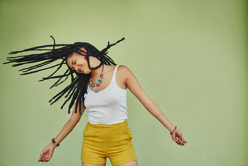Studio shot of an attractive young woman tossing her hair against a green background