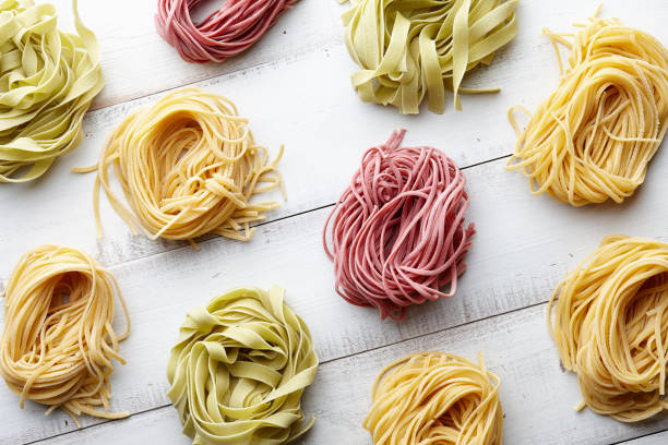 diversi tipi di pasta italiana su sfondo bianco legno - italian cuisine dry pasta directly above foto e immagini stock