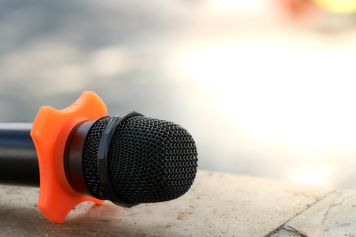 The microphone is placed on an orange stand. The background is light. There is space to fill the text. Show the publicity. copy space.