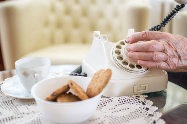 レトロな固定電話、自宅の電話番号をダイヤル シニア女性の手のクローズ アップ。 - landline phone women close up old fashioned ストックフォトと画像