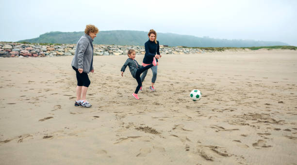 istock Three generations female playing soccer on the beach 855082664