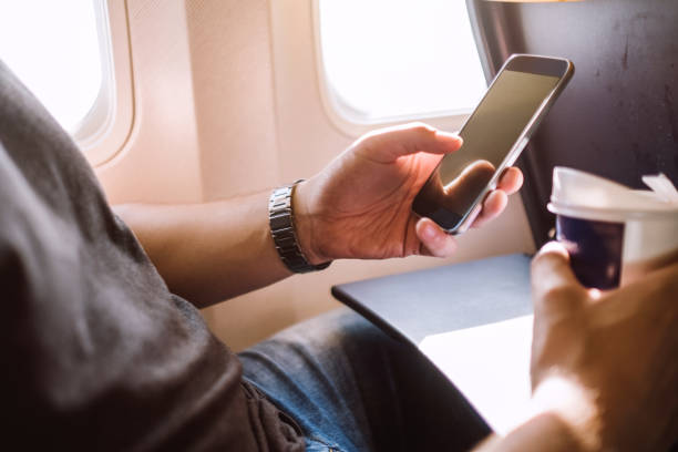 istock Young man text messaging on mobile phone in airplane 855086232