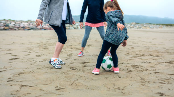 istock Three generations female playing soccer on the beach 855086370