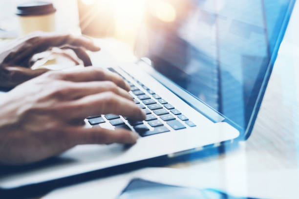 detailansicht der geschäftsmann im sonnigen büro auf modernen laptop arbeiten. männliche hände auf notebook-tastatur tippen. der hintergrund jedoch unscharf. sonnenlicht-effekte. - hinter stock-fotos und bilder