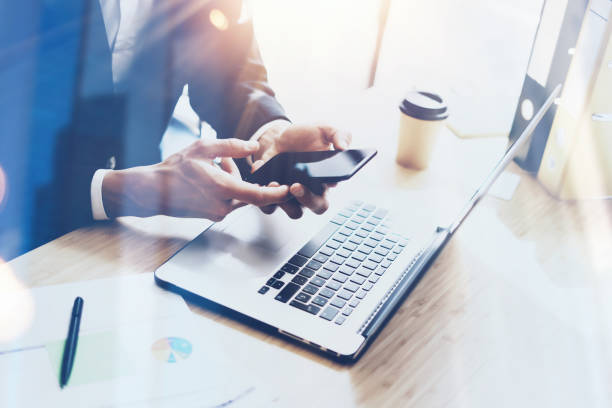 istock Businessman holding modern smartphone on hands.Coworker working at sunny office at work place.Visual effects.Blurred background. 855086582