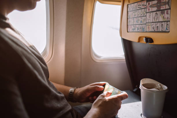istock Young man text messaging on mobile phone in airplane 855086932