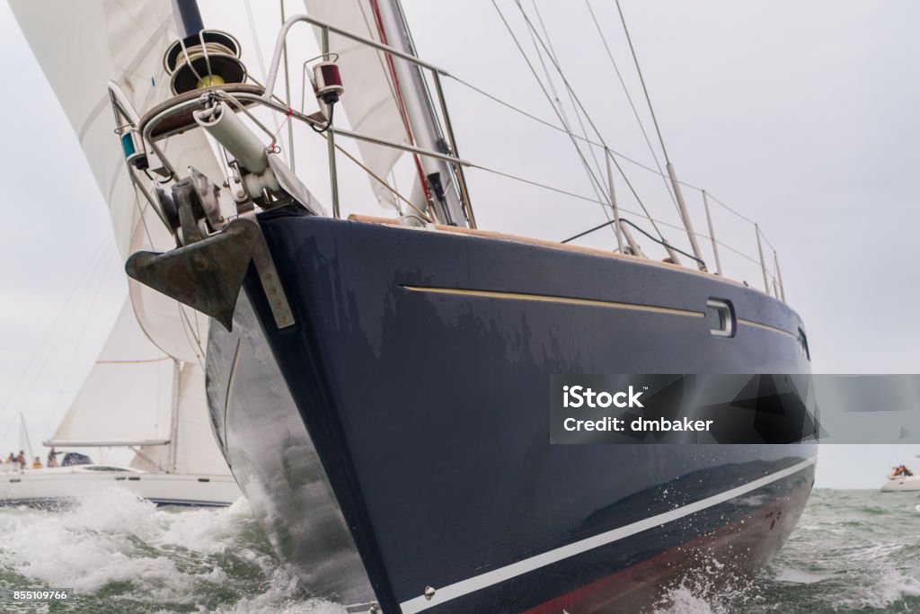 Extremo cerca encima de azul casco de velero, barco de vela o yate en el mar con otros barcos en el fondo - Foto de stock de Tormenta - Tiempo atmosférico libre de derechos