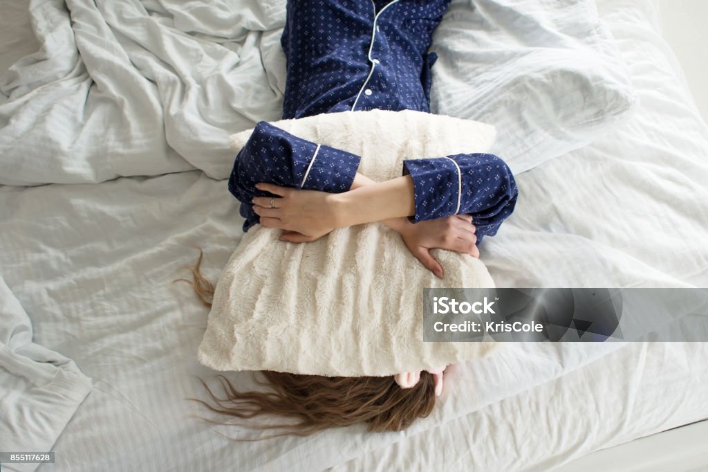 Zu faul, um aus dem Bett, deckt eine Frau ihr Gesicht mit einem Kissen - Lizenzfrei Schlaflosigkeit Stock-Foto