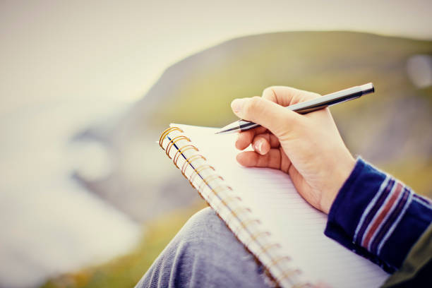 istock Cropped image of woman writing in diary against mountain 855120652