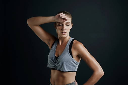 Studio shot of a fit young woman taking a break after a workout against a dark background