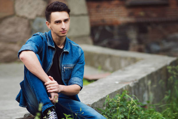 istock young guy in denim, walks on the street, sit 855127514