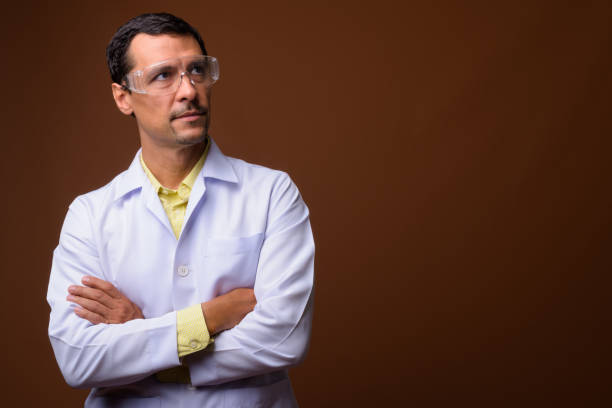 Studio shot of handsome man doctor wearing protective eyeglasses against colored background