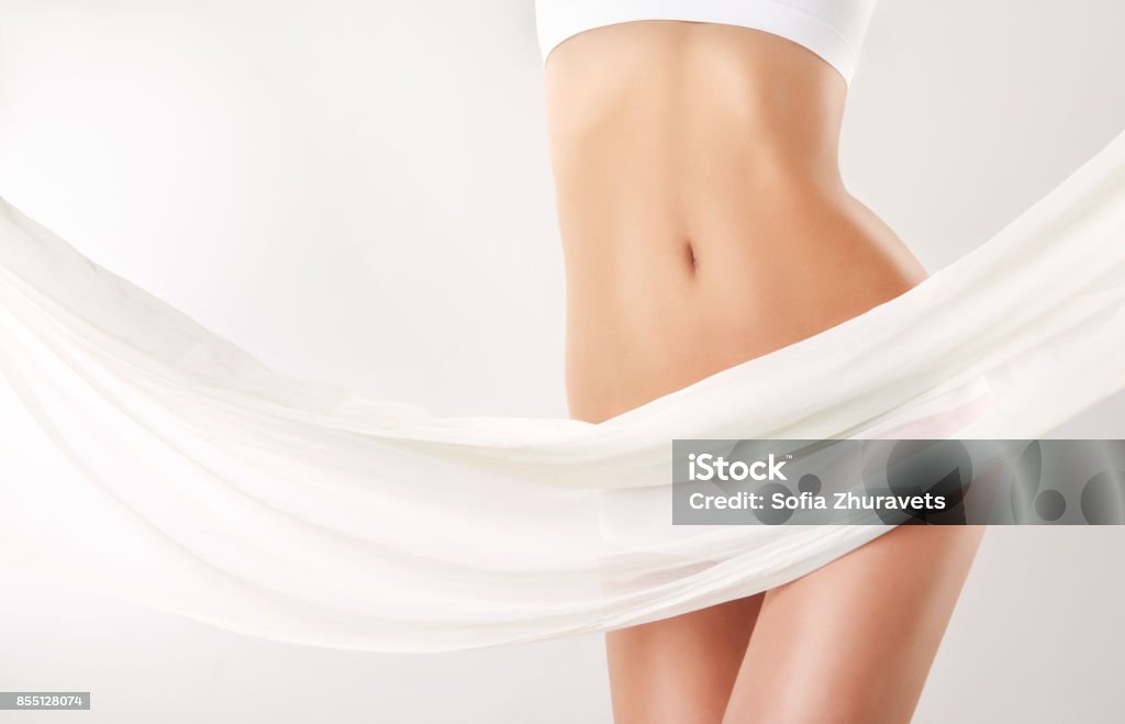 Graceful female body covered by tender, silk textile.  Alluring and healthy woman belly and hips.. Part of attractive woman body, hips and slender toned belly, covered by tender, silk textile. Graceful female figure, as a symbol of health and harmony. Bikini Stock Photo