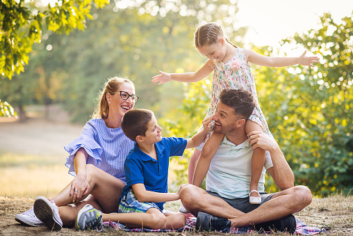 It is sunny day in late summer or early autumn, families using their free time to go to nature or city parks. Relaxed parenting and bonding with children while doing outdoor activities is great thing for parents.