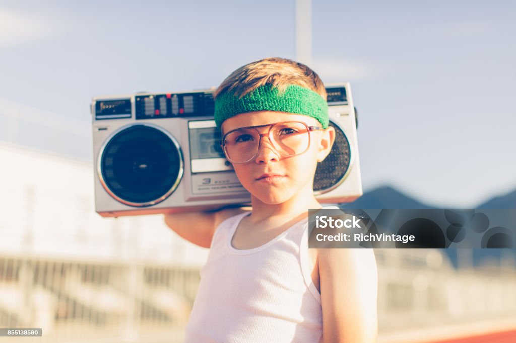 Young Retro Fitness Boy Listening to Music A young boy dressed in headband and retro workout attire is having a great time listening to music on his boombox. He has a serious expression on his face and is excited for health. Child Stock Photo