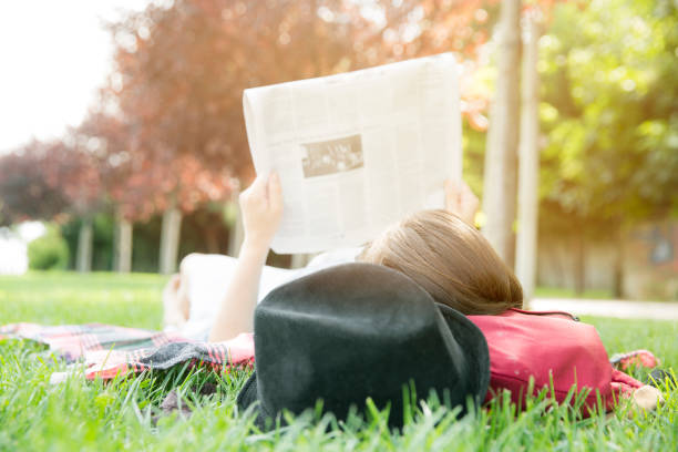 istock woman reading newspaper lying on the grass 855141890