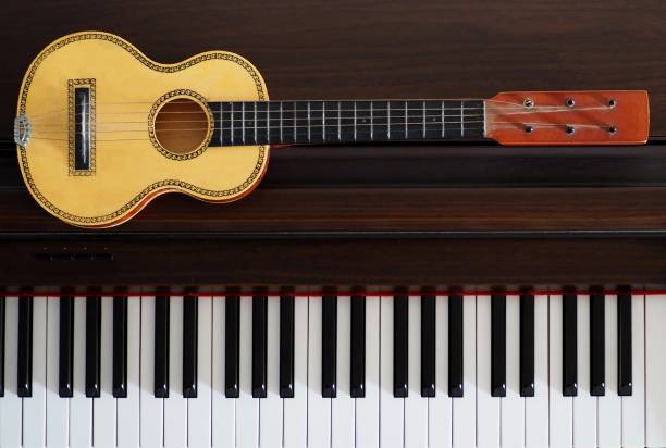 istock Old ukulele next to a piano keyboard 855142244
