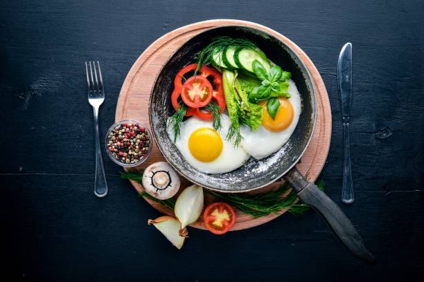 istock Fried egg with herbs and vegetables in a frying pan. Top view. Free space. 855155930