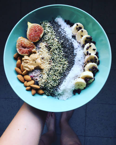 Young Woman Holding an Oatmeal Bowl Young Woman Holding an Oatmeal Bowl with Fruit and Seeds for Breakfast eating chia seeds stock pictures, royalty-free photos & images