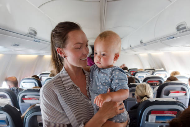 Mother and baby traveling on plane. Happy mother with a baby in her arms flying on a plane on vacation