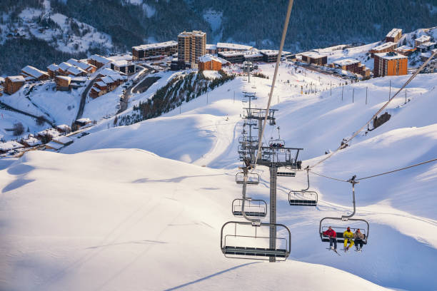 Skiers ascend on ski lift at Orcieres resort in Hautes-Alpes France Skiers ascend on ski lift chairs at the Orcieres ski resort located in Hautes-Alpes department, southern France. hautes alpes photos stock pictures, royalty-free photos & images