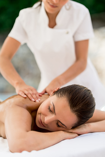 Beautiful woman relaxing with a back massage at the spa - luxury lifestyle concepts