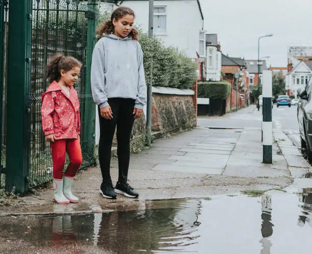 Stock photo of 2 sisters jumping in puddles. File has a signed model released.