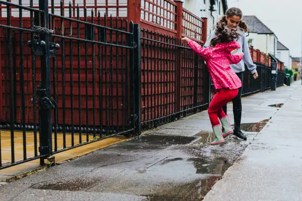 Stock photo of 2 sisters jumping in puddles. File has a signed model released.