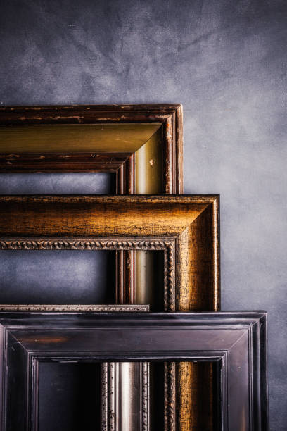 istock Assortment of empty old picture frames leaning against gray wall 855191448