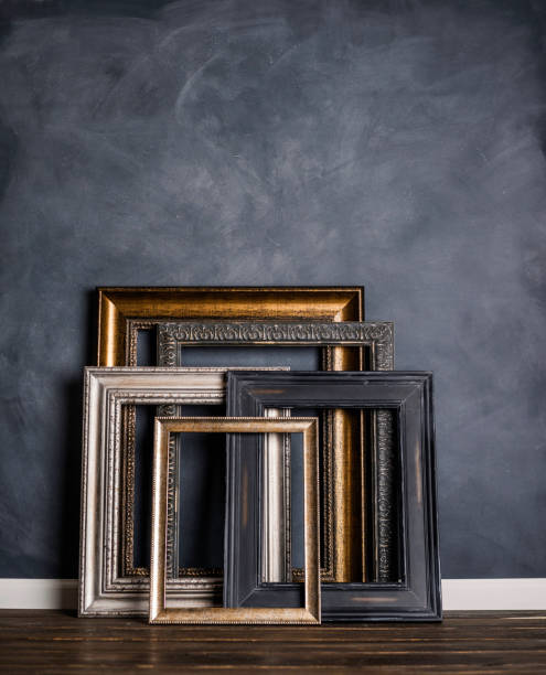 istock Assortment of empty old picture frames leaning against gray wall 855191692
