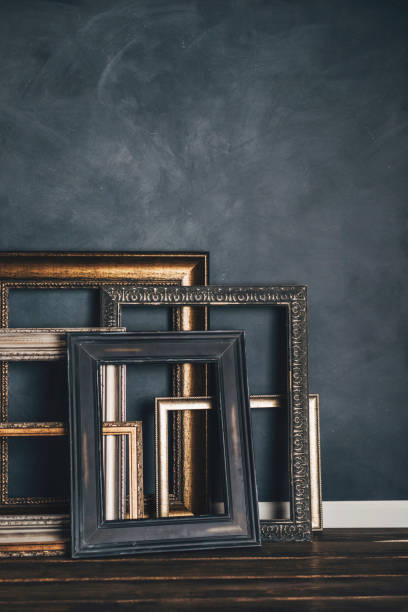 istock Assortment of empty old picture frames leaning against gray wall 855192118