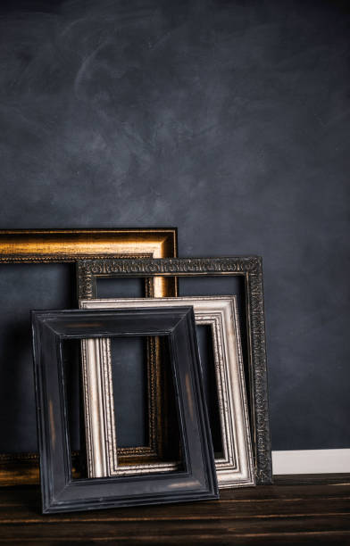 istock Assortment of empty old picture frames leaning against gray wall 855194354