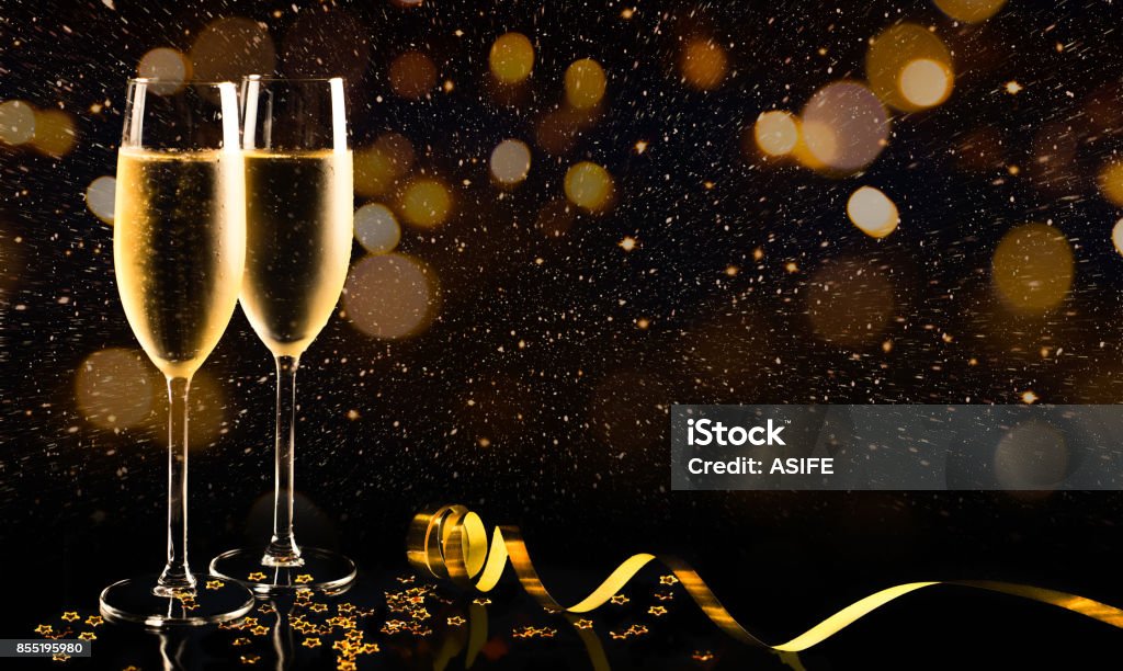 New year celebration with champagne Two glasses of champagne with golden confetti, glitter, serpentine and lights. Night of celebration concept Champagne Stock Photo