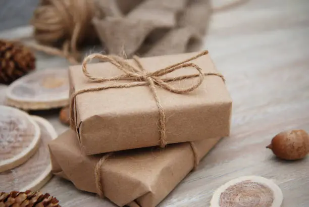 Photo of Christmas gift or present box wrapped in kraft paper with Decoration on Rustic Wooden Background.