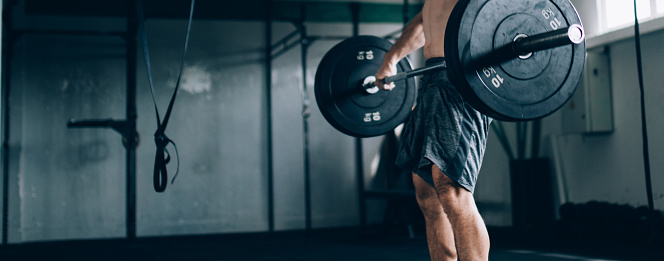 Close-up of a bodybuilder exercising with barbells in the gym