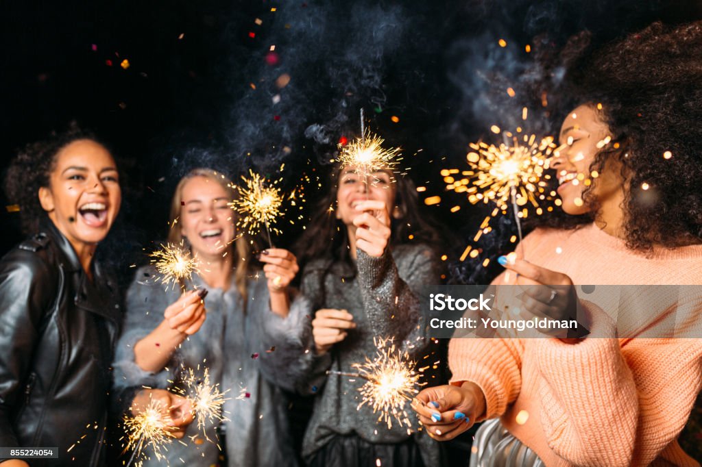 Four happy women holding sparklers, throwing confetti Sparkler - Firework Stock Photo